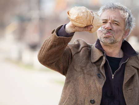 Homeless man drinking. Depressed senior man drinking alcohol on streetの写真素材