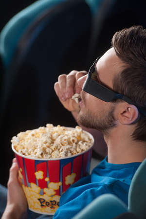 Men at cinema. Top view of excited young men in glasses watching movie at the cinema and eating popcornの写真素材