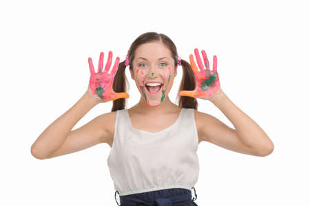 Happy teenage girl. Excited young woman with pigtails showing her hands stained in paint while isolated on whiteの写真素材