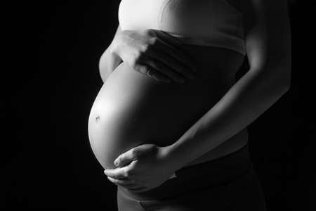 Pregnancy. Black and white image of pregnant woman touching her abdomenの写真素材