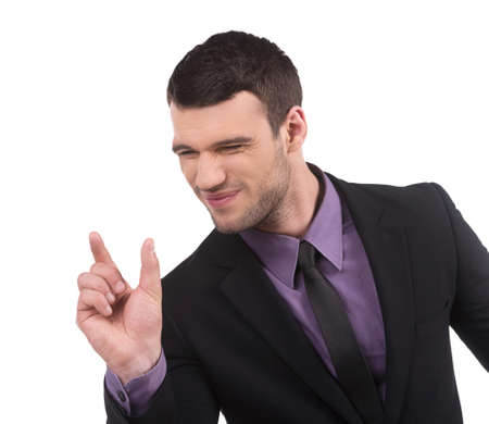 Showing the size. Confident young man in formalwear showing the size of something by fingers while isolated on whiteの写真素材