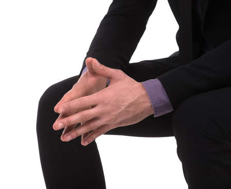 Hands clasped. Close-up of businessman keeping his hands clasped while sitting isolated on whiteの写真素材