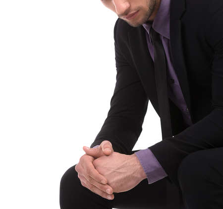 Thoughtful businessman. Pensive young man in formalwear sitting and holding his hands clasped while isolated on whiteの写真素材