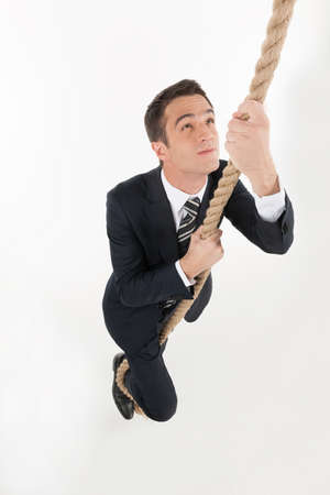 Businessmen competition. Top view of businessman rising up by rope while isolated on whiteの写真素材