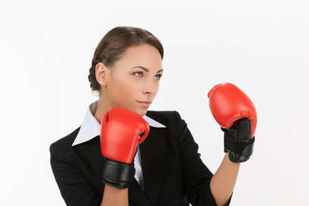 Businesswomen in boxing gloves. Beautiful young businesswomen in red boxing gloves posing while isolated on whiteの写真素材