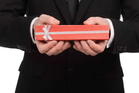 Businessman holding a red gift box in his hands standing against white backgroundの写真素材