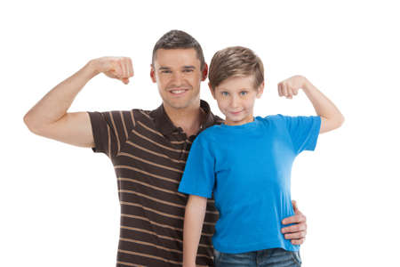 Father and son. Cheerful father and son standing close to each other and showing their musculature while isolated on whiteの写真素材