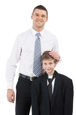 Father and son. Cheerful father in formalwear and son standing close to each other while isolated on whiteの写真素材