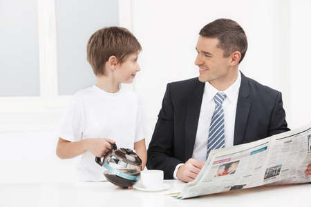 Father and son. Cheerful child pouring coffee for his fatherの写真素材