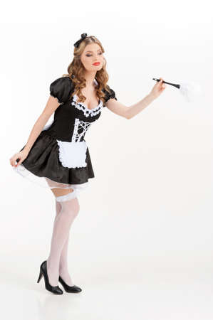 Sexy maid. Beautiful young maid in white pantyhose holding brush and looking awayの写真素材