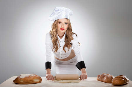 Sexy cook. Beautiful young woman in Chef costume standing isolated on greyの写真素材