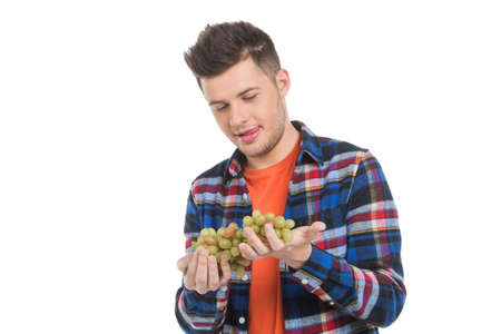 Men with grapes. Cheerful young men holding grapes and looking at it while standing isolated on...