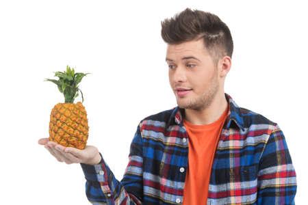 Men with grapes. Cheerful young men holding pineapple and looking at it while standing isolated on whiteの写真素材
