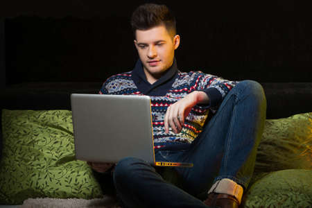 Men surfing web. Handsome young men using computer while sitting on the couchの写真素材