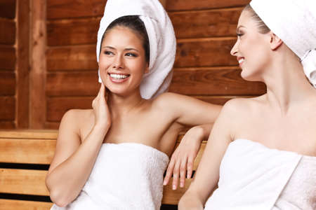 Two beautiful laughing females sitting and talking in saunaの写真素材