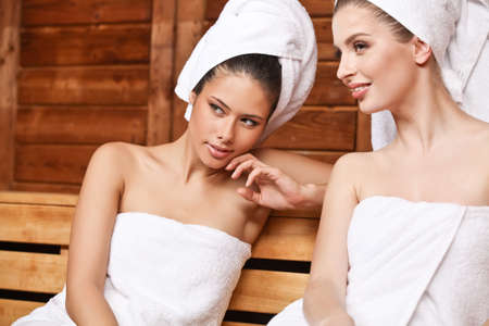 Two beautiful laughing females sitting and talking in saunaの写真素材