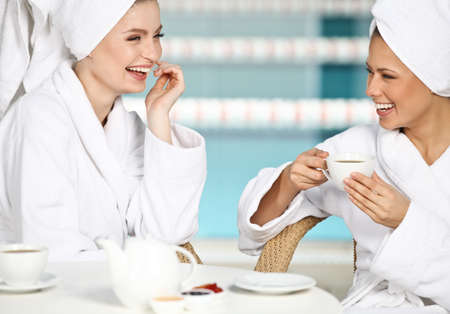 Two beautiful young girls having fun at spa salonの写真素材
