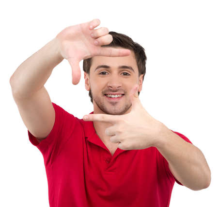 Finger frame. Cheerful young man looking through a finger frame in front of her face while isolated on whiteの写真素材