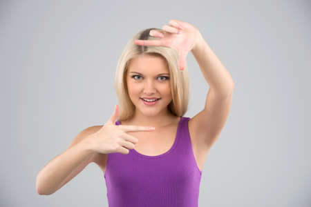 Finger frame. Cheerful young woman looking through a finger frame in front of her face while...