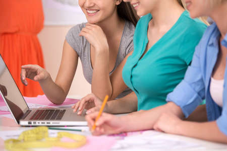 Fashion designers at work. Cropped image of three cheerful young women working at fashion design studioの写真素材
