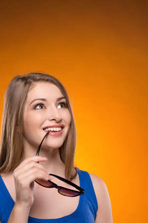 Cheerful women. Beautiful young women holding glasses and smiling while isolated on coloured backgroundの写真素材