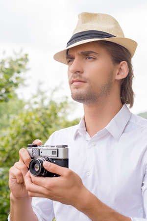 Man with camera. Thoughtful young man holding camera in his hands and looking awayの写真素材