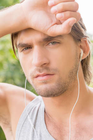 Tired man. Portrait of tired young man with headphones looking at cameraの写真素材