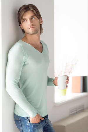 Man with cup. Thoughtful young man holding cup and looking awayの写真素材