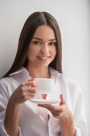 Beauty drinking coffee. Beautiful young woman drinking coffee and smilingの写真素材