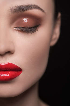 Close-up cropped image of beautiful women with make-up keeping eyes closed while isolated on blackの写真素材