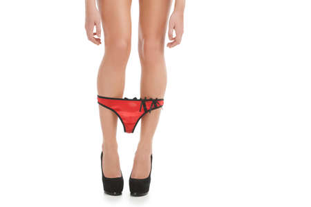 Red panties. Cropped image of young women in black shoes taking down her red panties while standing isolated on whiteの写真素材
