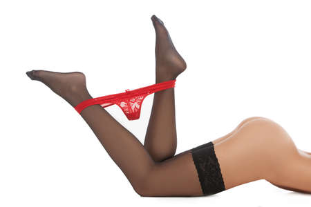 Red panties. Cropped image of young women taking down her white panties while isolated on whiteの写真素材