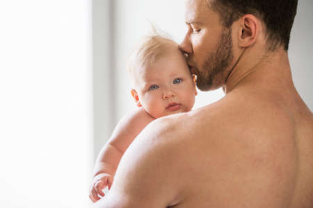 Man with baby. Young muscular man holding baby and kissing himの写真素材