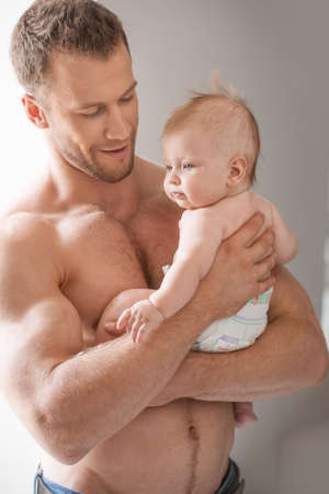 Man with baby. Young muscular man holding baby in his hands and smilingの写真素材