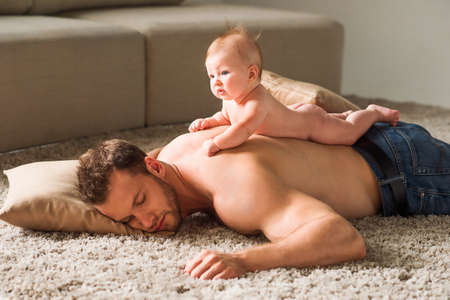 Tired father. Little baby lying on fathers back while manの写真素材