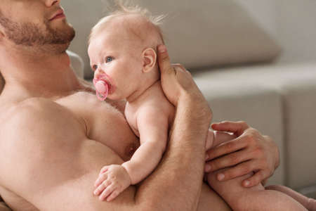 Man with baby. Cropped image of young muscular man holding baby in his handsの写真素材