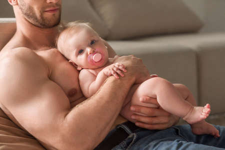 Man with little baby. Cropped image of young muscular man holding baby in his handsの写真素材