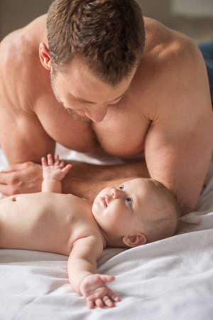 Man with little baby. Young muscular man and little baby looking at each other and smilingの写真素材
