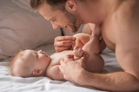 Man with baby. Young muscular man playing with little babyの写真素材