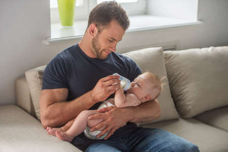 Man with baby. Young muscular man feeding little babyの写真素材