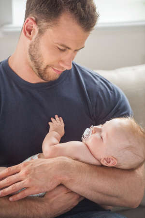 Man with baby. Young muscular man holding baby in his hands and smilingの写真素材