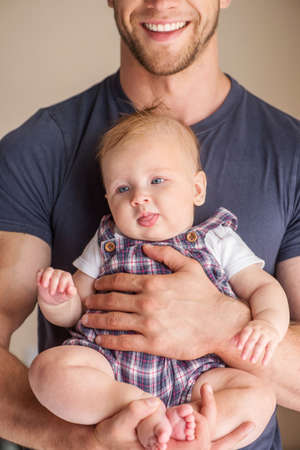 Man with baby. Young muscular man holding baby in his hands and smilingの写真素材