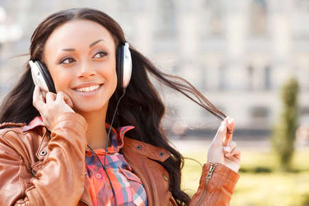 Music lover. Young African descent woman in headphones listening to the music and smilingの写真素材