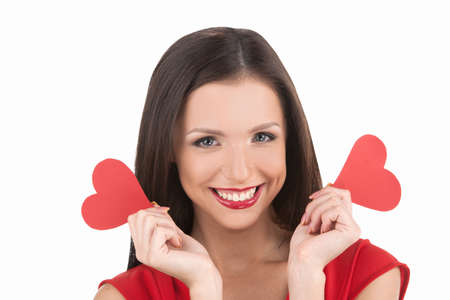 Girl with gift box. Beautiful young woman holding paper hearts and smiling at camera while isolated on whiteの写真素材