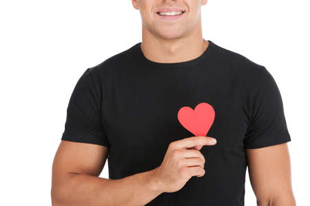 Man with paper heart  Cropped image of handsome young man holding a paper heart while standing...