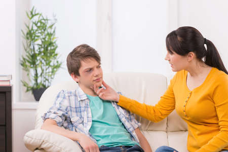 Mother and problem child. Frustrated mother the injured face of her son sitting on the couchの写真素材