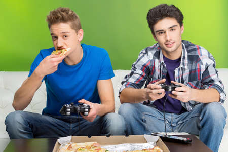 Two young gamers playing video games while sitting on the couch
