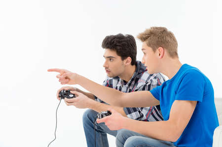 Side view of two young gamers playing video games while isolated on whiteの写真素材