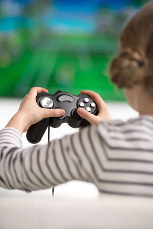Girl with joystick. Rear view of little girl playing video gameの写真素材