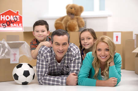 Happy family. Cheerful family lying together near the cardboard boxes and smilingの写真素材